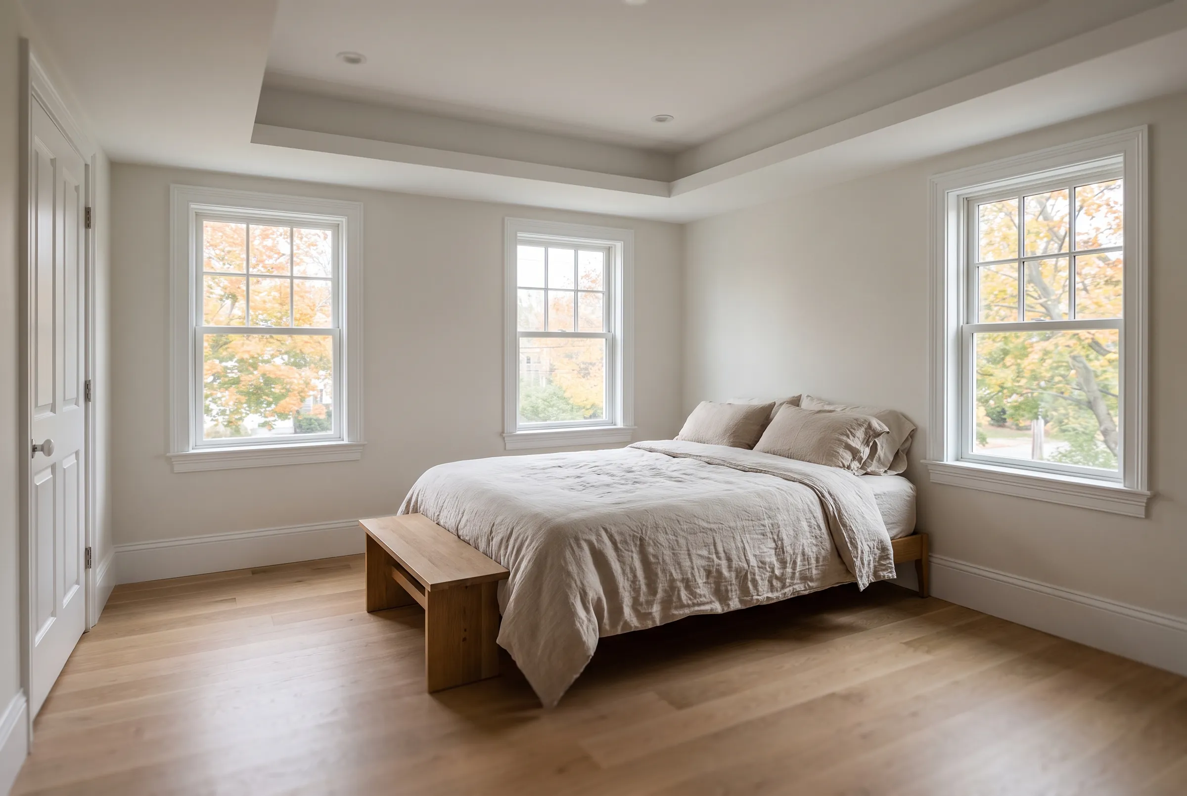 A finished bedroom inside a second-floor addition, with oak floors and a tray ceiling